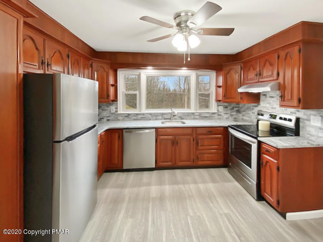 7522 Old Coach Road Stroudsburg, PA 18360 - Photo 16 of 68 a kitchen with stainless steel appliances granite countertop a refrigerator a sink dishwasher a stove with wooden cabinets and floor