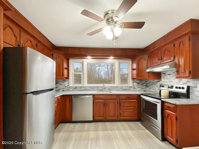 7522 Old Coach Road Stroudsburg, PA 18360 - Photo 19 of 68 a kitchen with stainless steel appliances granite countertop a stove a sink dishwasher a refrigerator and a dining table with wooden floor