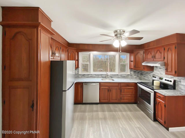 7522 Old Coach Road Stroudsburg, PA 18360 - Photo 26 of 68 a kitchen with stainless steel appliances granite countertop a refrigerator a stove a sink and dishwasher with wooden cabinets