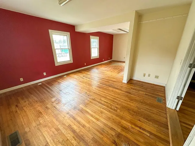 a view of an empty room with window and wooden floor