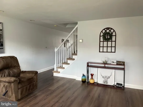 a living room with couches and a potted plant with wooden floor