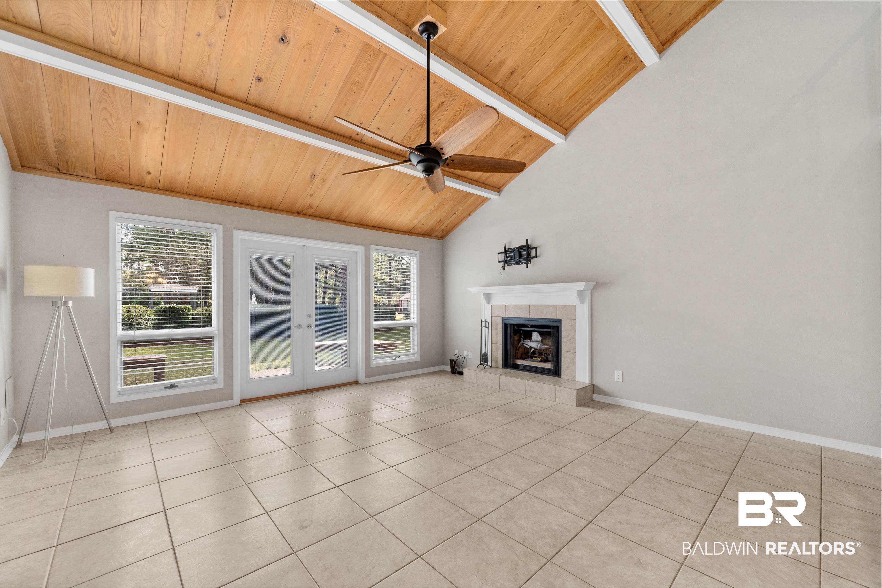 1701 Regency Road, Unit 111 Gulf Shores, AL 36542 - Photo 6 of 29 Unfurnished living room featuring french doors, wood ceiling, a tile fireplace, ceiling fan, and beamed ceiling