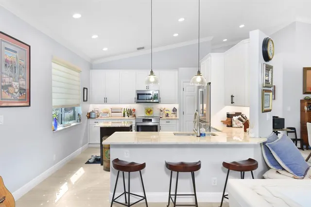a kitchen with stainless steel appliances granite countertop a stove and a sink with couches wooden floor