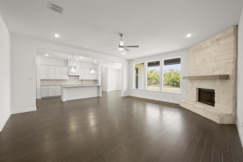 27 Old Crow Road Joshua, TX 76058 - Photo 10 of 35 an empty room with wooden floor kitchen view and a fireplace