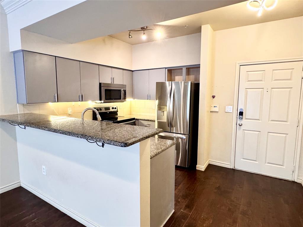 3102 Kings Road, Unit 2106 Dallas, TX 75219 - Photo 5 of 20 a kitchen with stainless steel appliances granite countertop a refrigerator a stove and a sink with wooden floor