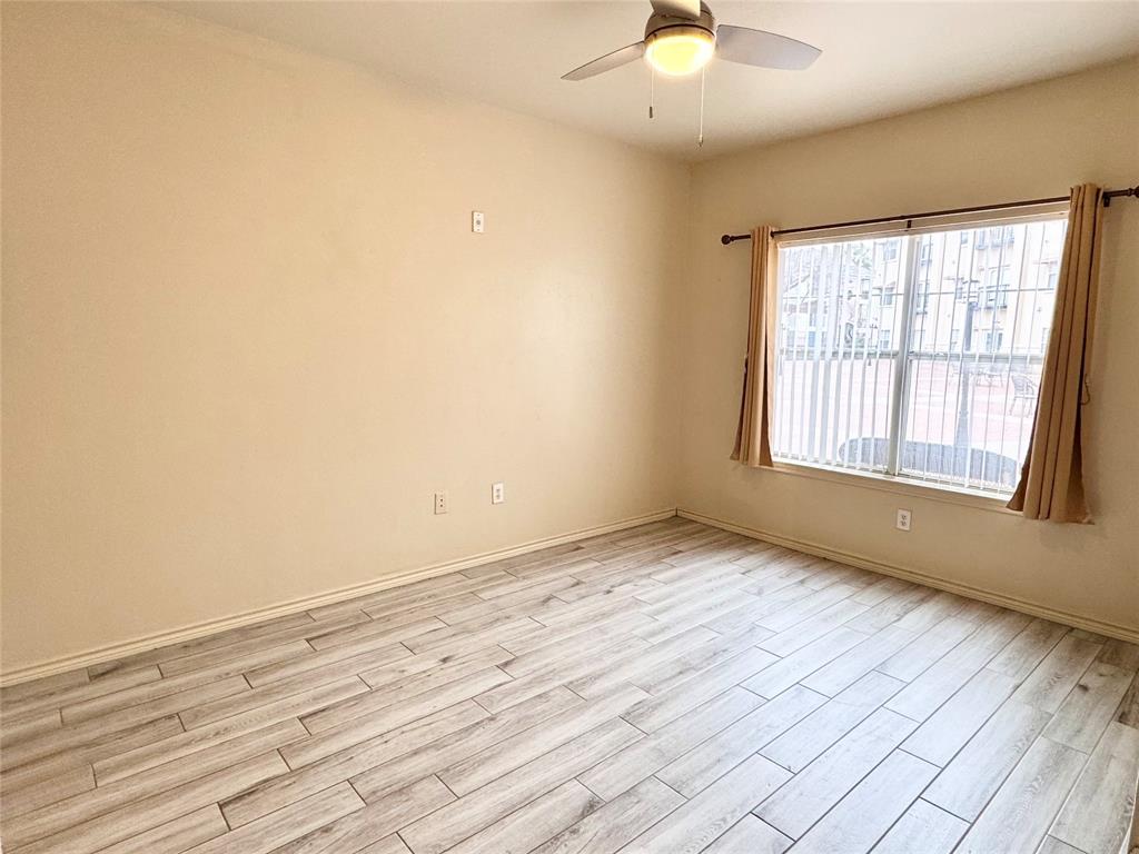 3102 Kings Road, Unit 2106 Dallas, TX 75219 - Photo 9 of 20 an empty room with wooden floor chandelier fan and windows