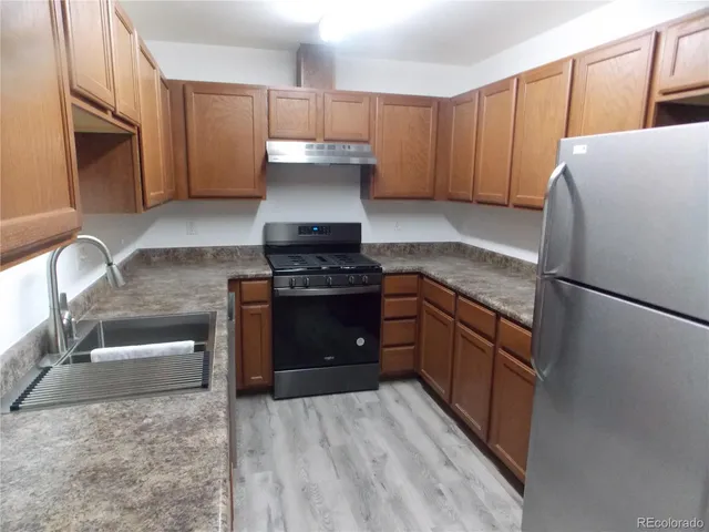 a kitchen with granite countertop a refrigerator stove and sink