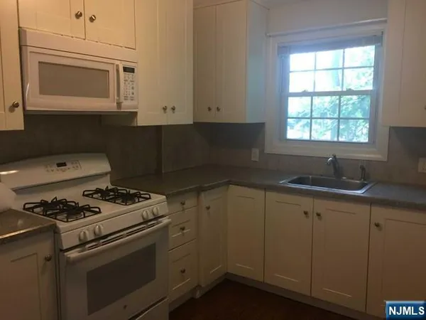 a kitchen with cabinets appliances a sink and a window