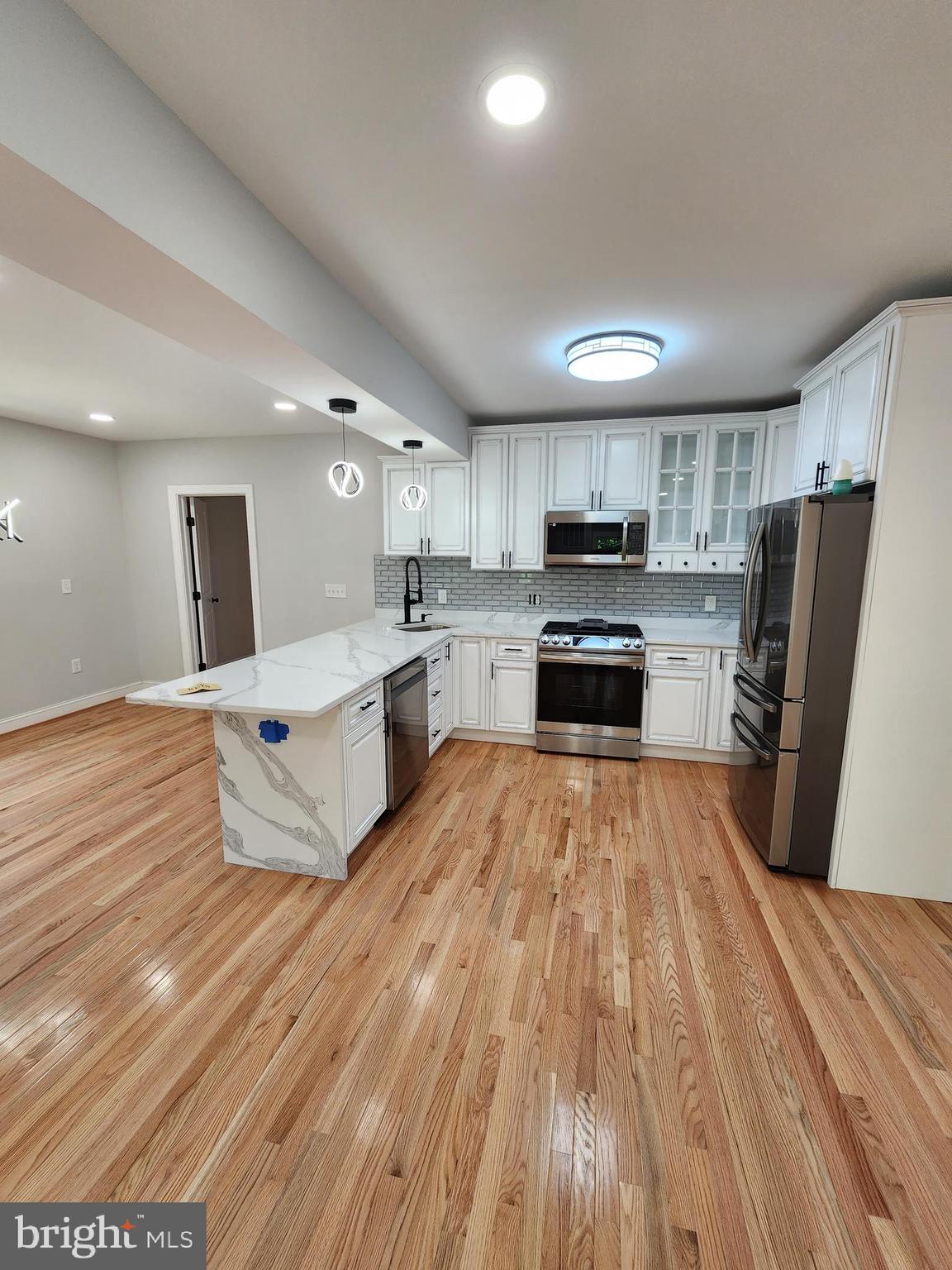 a large kitchen with a stove a sink dishwasher a refrigerator and wooden floor