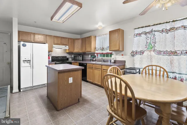 a kitchen with stainless steel appliances granite countertop a table chairs sink refrigerator and cabinets