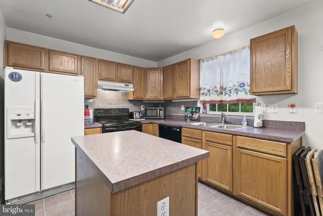 a kitchen with a refrigerator a sink a stove a microwave and cabinets