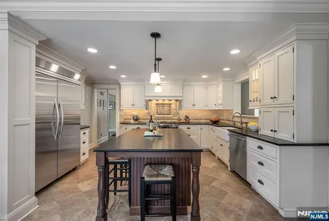 a kitchen with stainless steel appliances granite countertop a sink refrigerator and cabinets