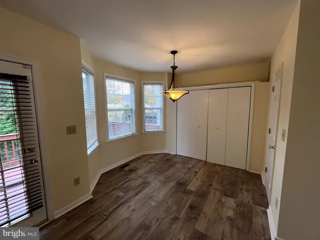 a view of an empty room with window and wooden floor