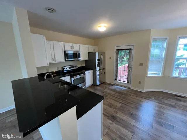 a kitchen with granite countertop a refrigerator and a stove top oven