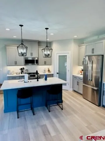 a kitchen with stainless steel appliances kitchen island granite countertop a sink refrigerator and cabinets
