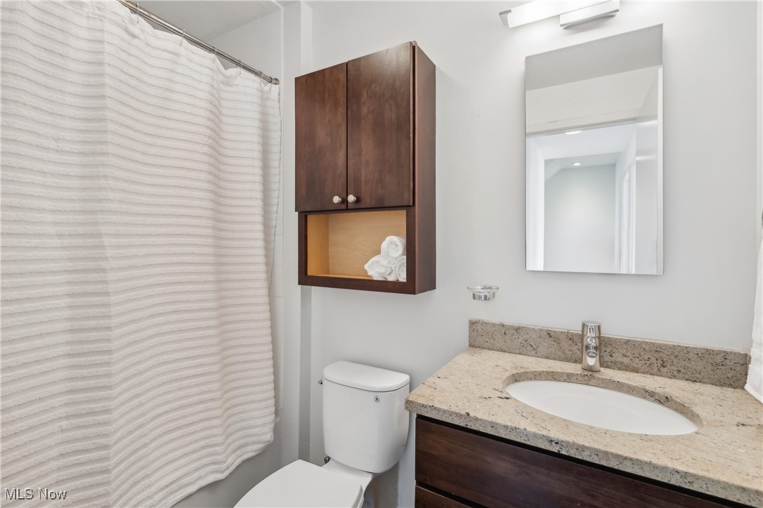 1852 Coltman Road Cleveland, OH 44106 - Photo 17 of 39 Full bath featuring vanity with stone counters, a shower with shower curtain, and toilet