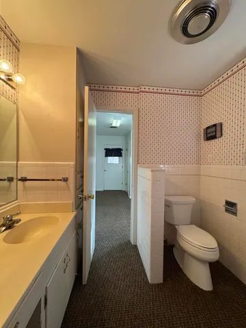 a bathroom with a granite countertop sink a toilet and shower