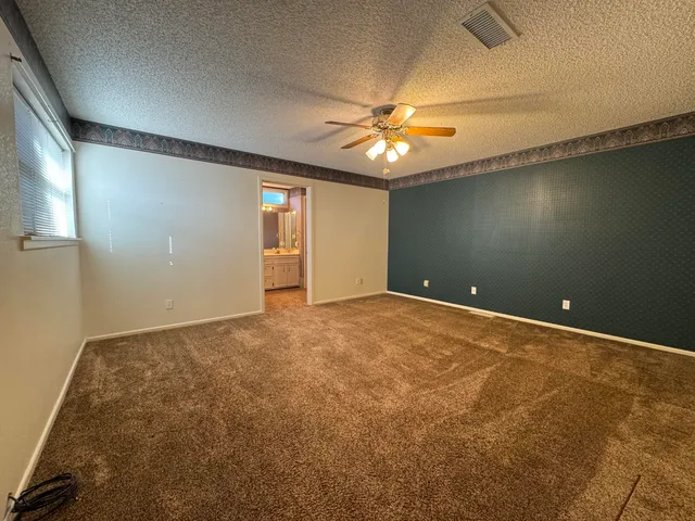 an empty room with a ceiling fan and carpet