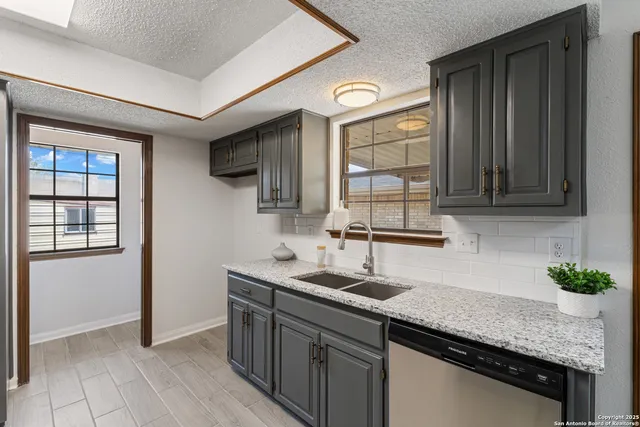 a kitchen with granite countertop stainless steel appliances a sink stove and cabinets
