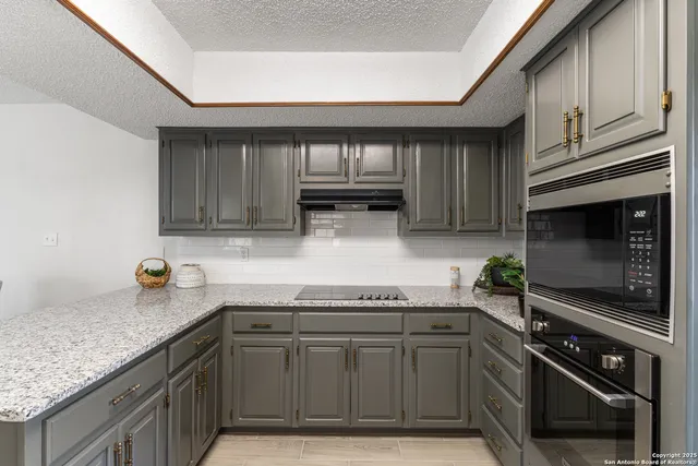 a kitchen with granite countertop a cabinets and steel stove top oven