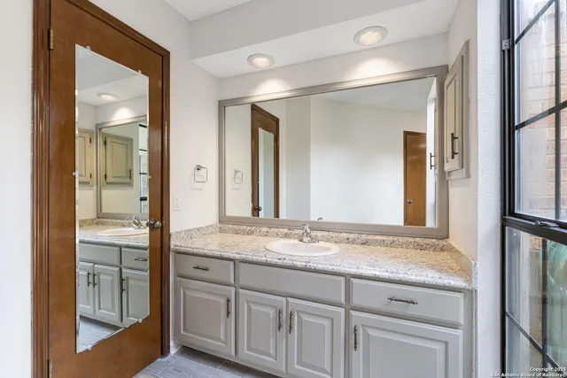 a bathroom with a granite countertop sink and a mirror
