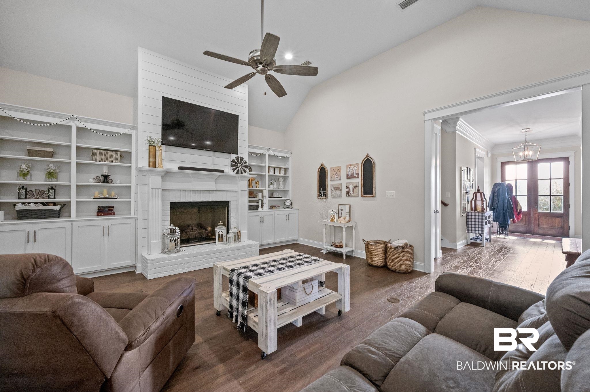32194 Badger Court Daphne, AL 36527 - Photo 11 of 49 Living room with lofted ceiling, a fireplace, dark wood-style floors, a chandelier, and ceiling fan
