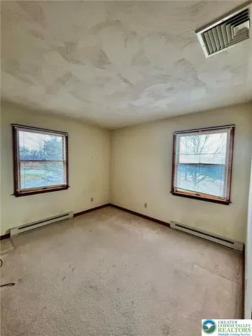 an empty room with windows and fireplace