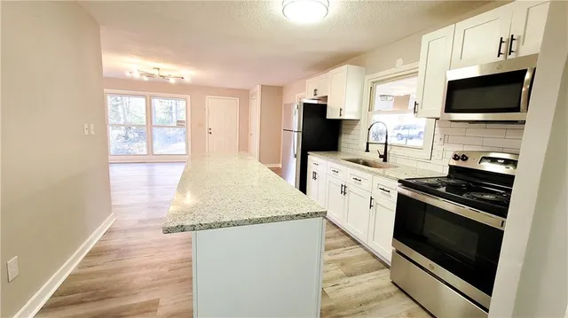 a kitchen with stainless steel appliances kitchen island granite countertop a stove a sink and a microwave