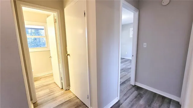 a view of a hallway with wooden floor and a bathroom