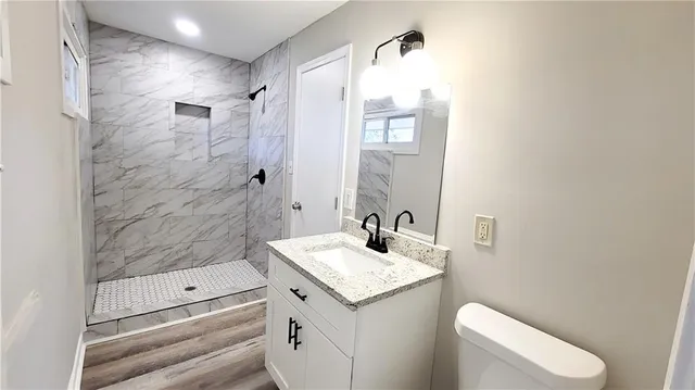 a bathroom with a granite countertop sink toilet and shower