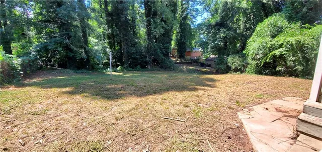a view of a yard with plants and trees
