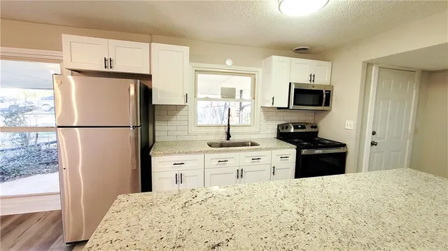a kitchen with granite countertop a refrigerator stove top oven and sink