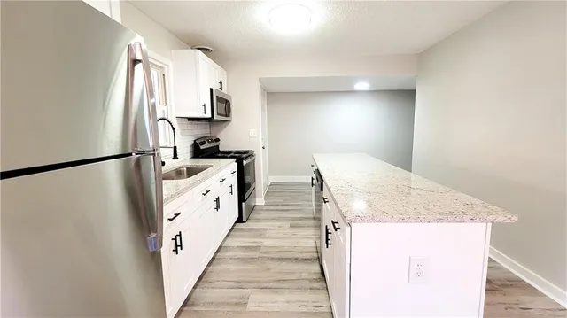 a kitchen with granite countertop white cabinets and white appliances