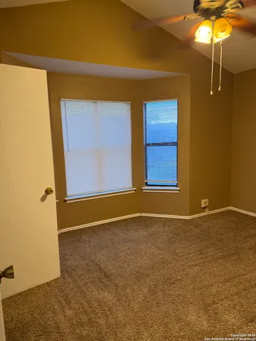 a view of an empty room with window and chandelier fan