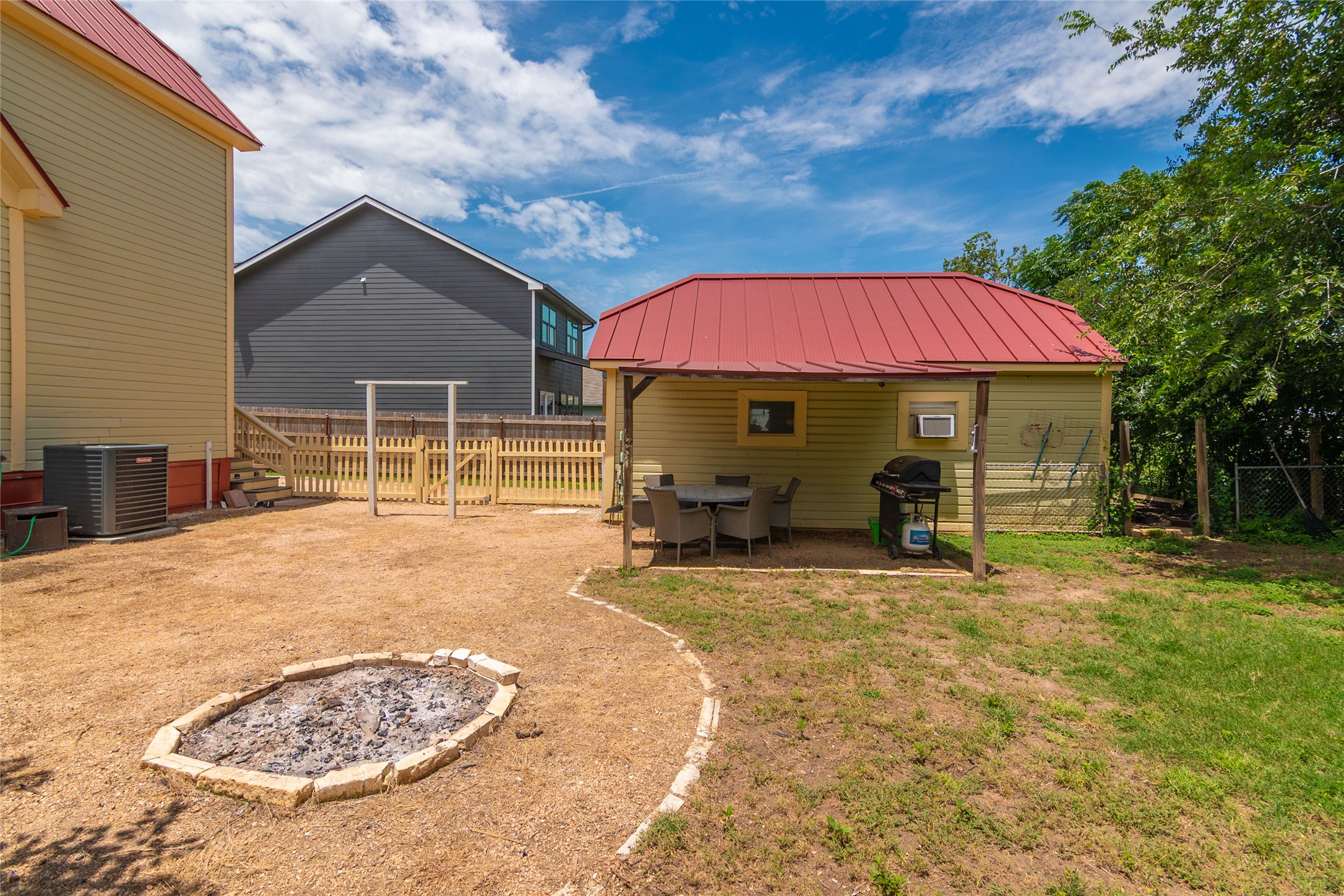 204 Prim Rose Road Blanco, TX 78606 - Photo 34 of 40 A spacious backyard features a built-in stone fire pit and a covered patio structure.