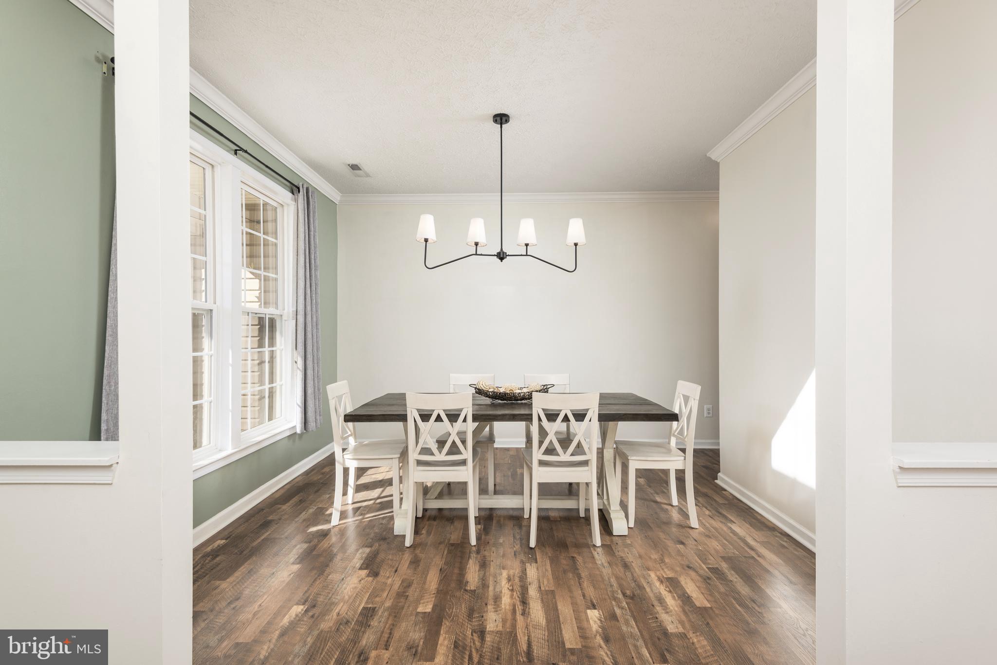 1208 Painted Fern Road Denton, MD 21629 - Photo 7 of 39 a dining room with wooden floor a chandelier a wooden table and chairs