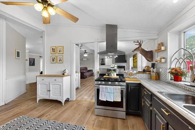 a kitchen with stainless steel appliances a stove cabinets and wooden floor