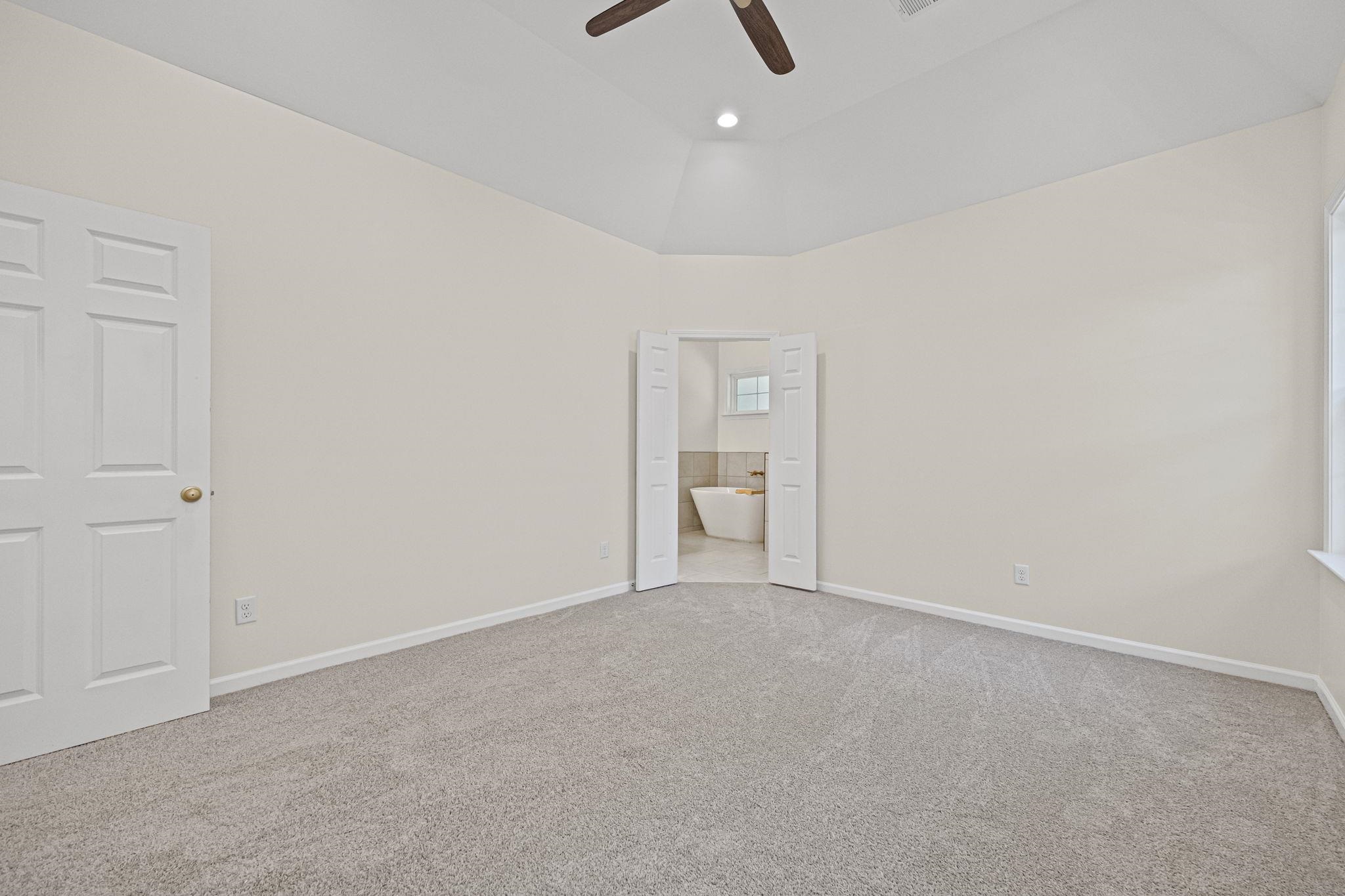 8670 Valmont Circle Memphis, TN 38016 - Photo 23 of 33 Unfurnished bedroom with light colored carpet, connected bathroom, ceiling fan, high vaulted ceiling, and recessed lighting