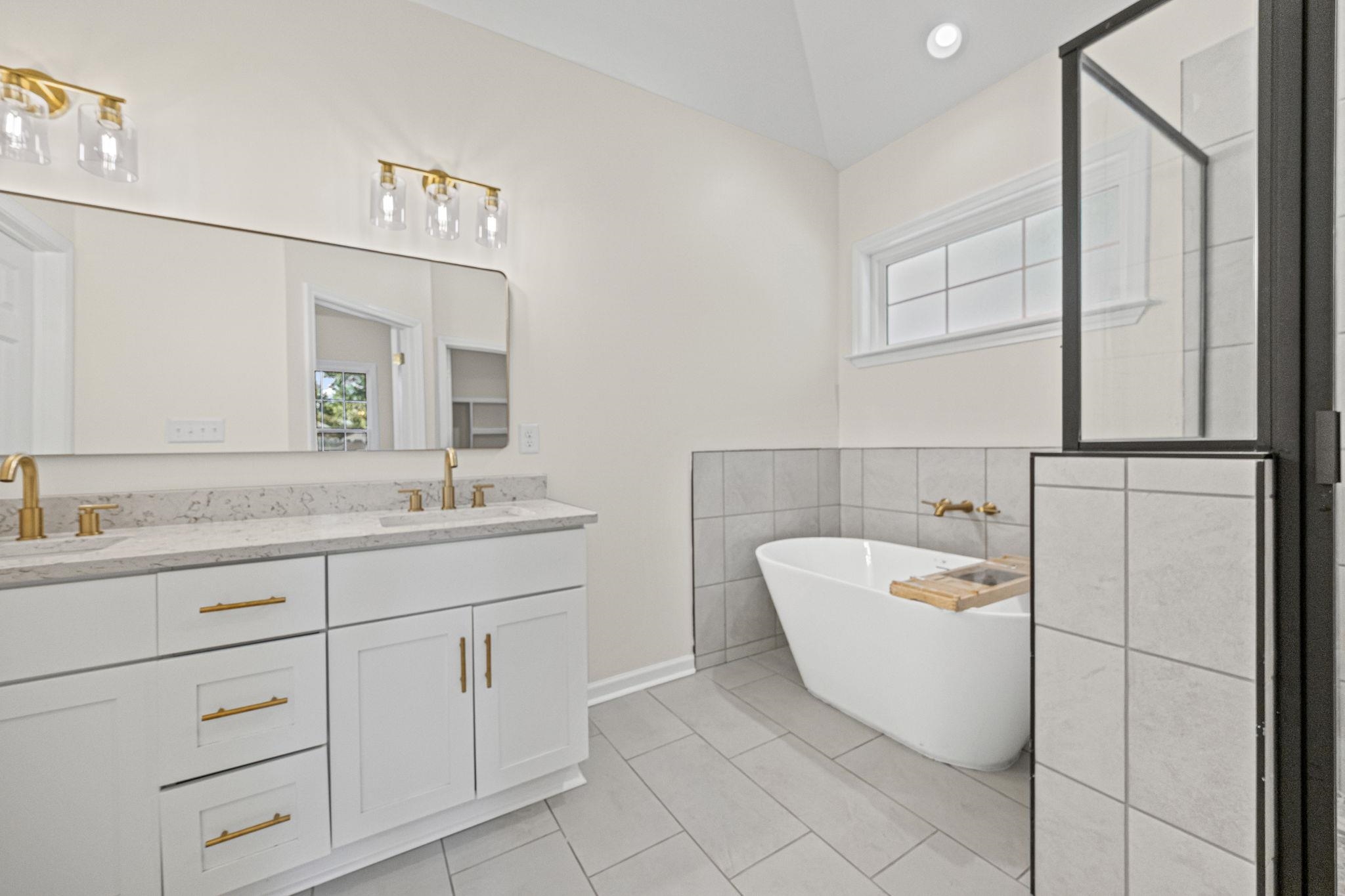 8670 Valmont Circle Memphis, TN 38016 - Photo 24 of 33 Bathroom with a freestanding bath, double vanity, light tile patterned floors, a shower stall, and tile walls