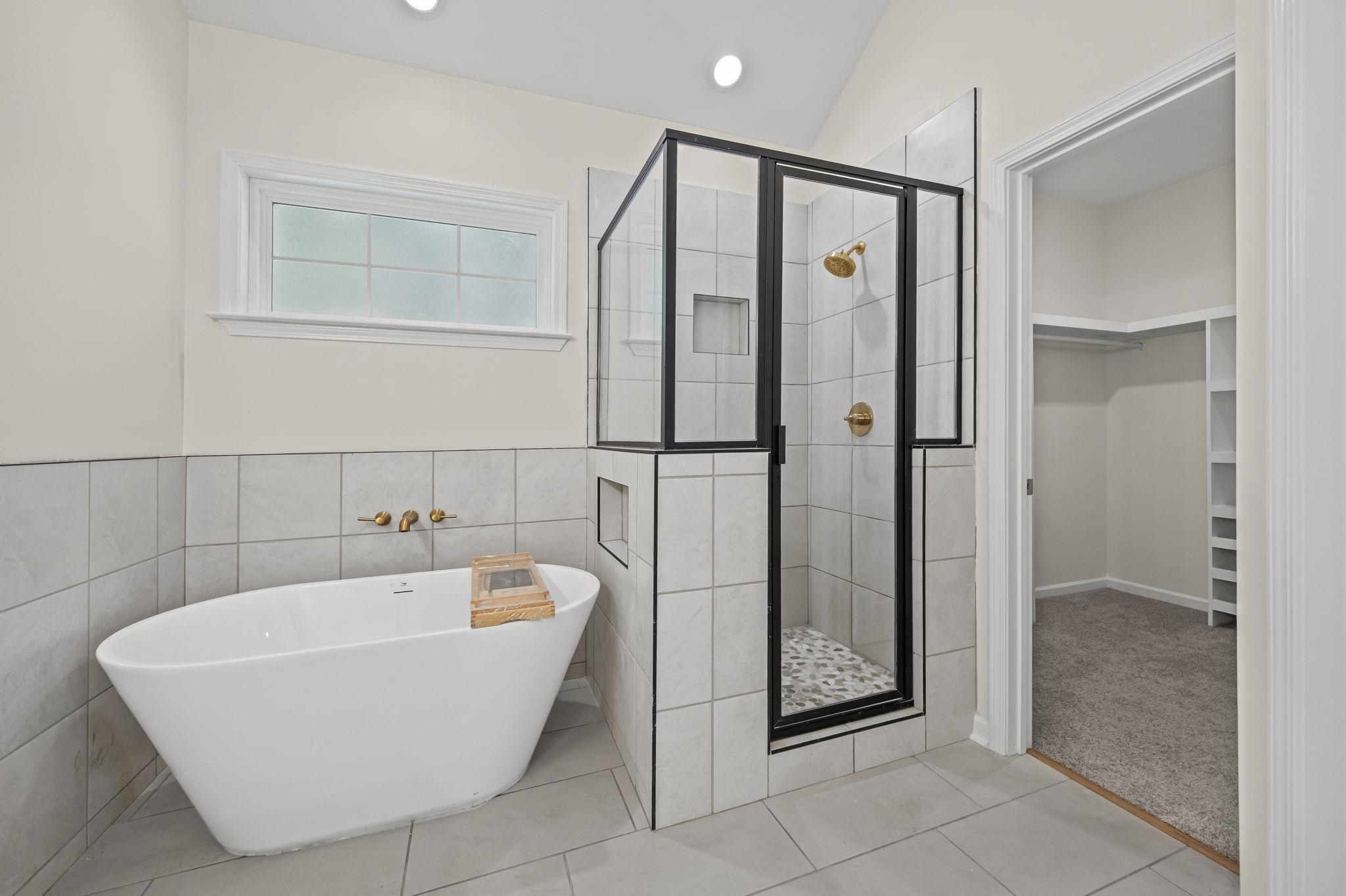 8670 Valmont Circle Memphis, TN 38016 - Photo 26 of 33 Full bathroom featuring a stall shower, a soaking tub, a spacious closet, light tile patterned floors, and tile walls