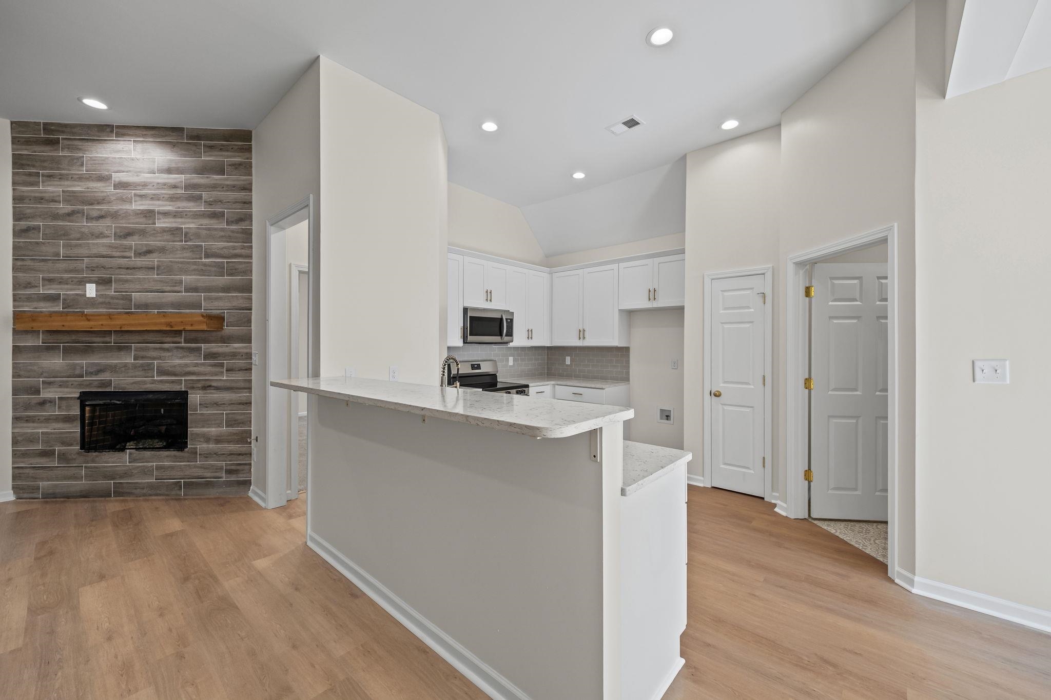 8670 Valmont Circle Memphis, TN 38016 - Photo 5 of 33 Kitchen featuring white cabinets, light stone counters, backsplash, stainless steel appliances, and light wood finished floors