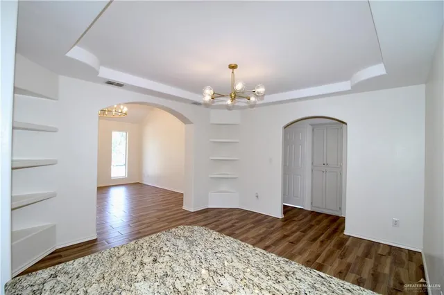 a view of a hallway with wooden floor and chandelier