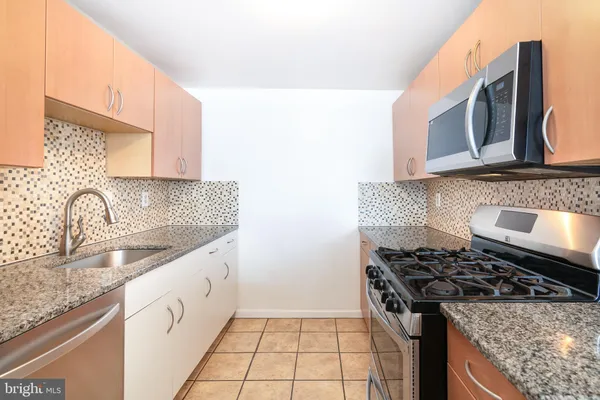 a kitchen with granite countertop a sink stove and cabinets
