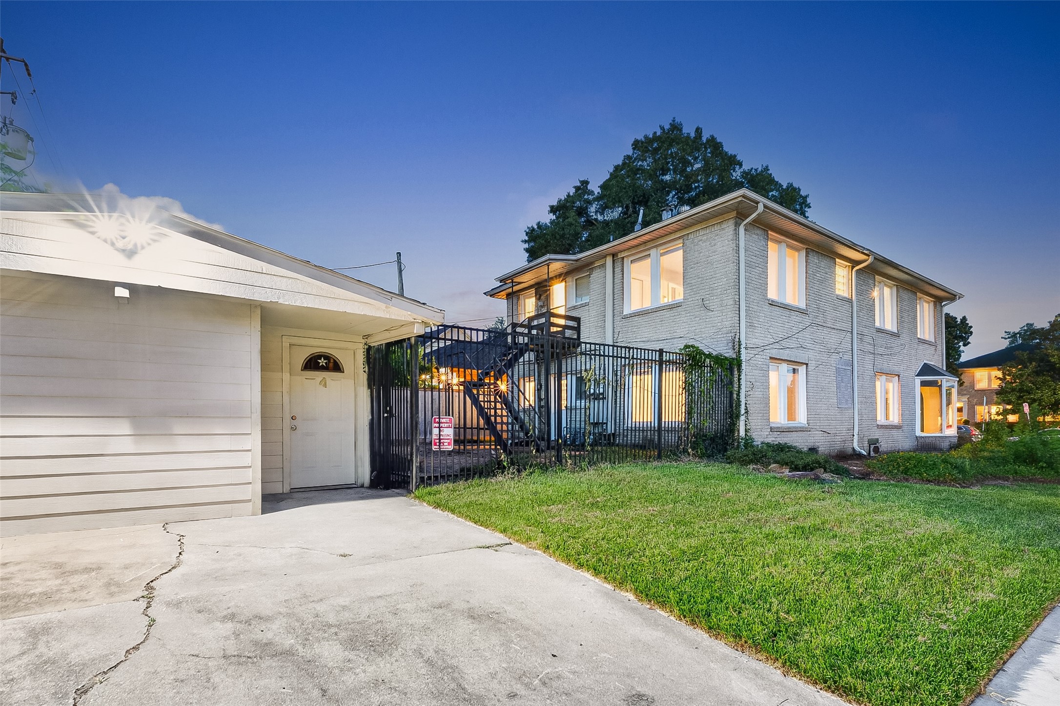 1758 Hawthorne Street, Unit 2 Houston, TX 77098 - Photo 18 of 19 This photo shows a two-story brick home with large windows, a well-maintained front yard, and a paved driveway leading to a detached garage. The property is illuminated, giving it a welcoming appearance.