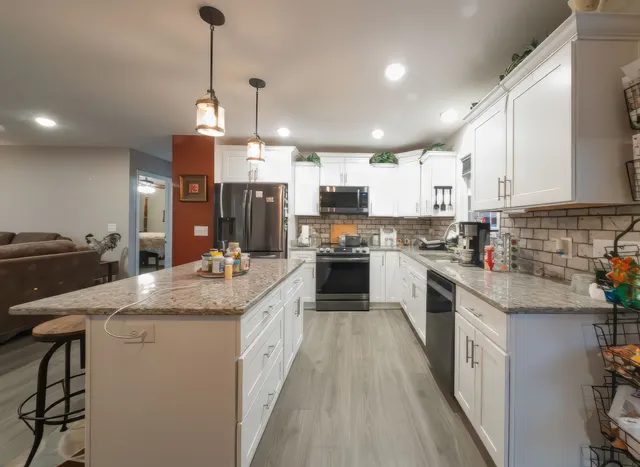 a kitchen with kitchen island granite countertop a sink a counter top space stainless steel appliances and cabinets