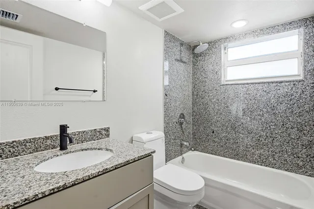 a bathroom with a granite countertop sink toilet and shower