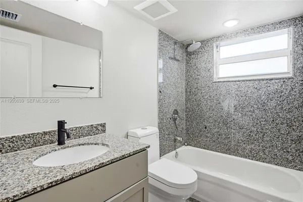 a bathroom with a granite countertop sink toilet and shower