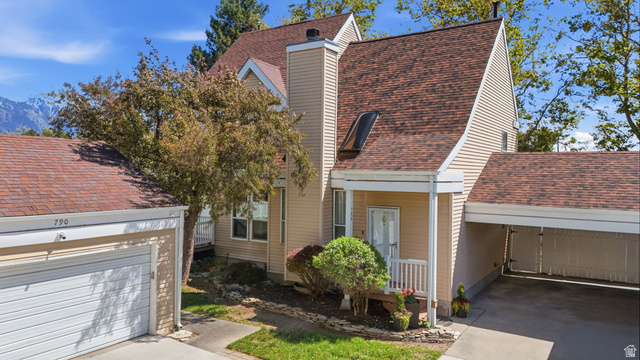 Multi-level residence featuring light-toned siding, a distinct red-brown shingle roof, and an integrated carport