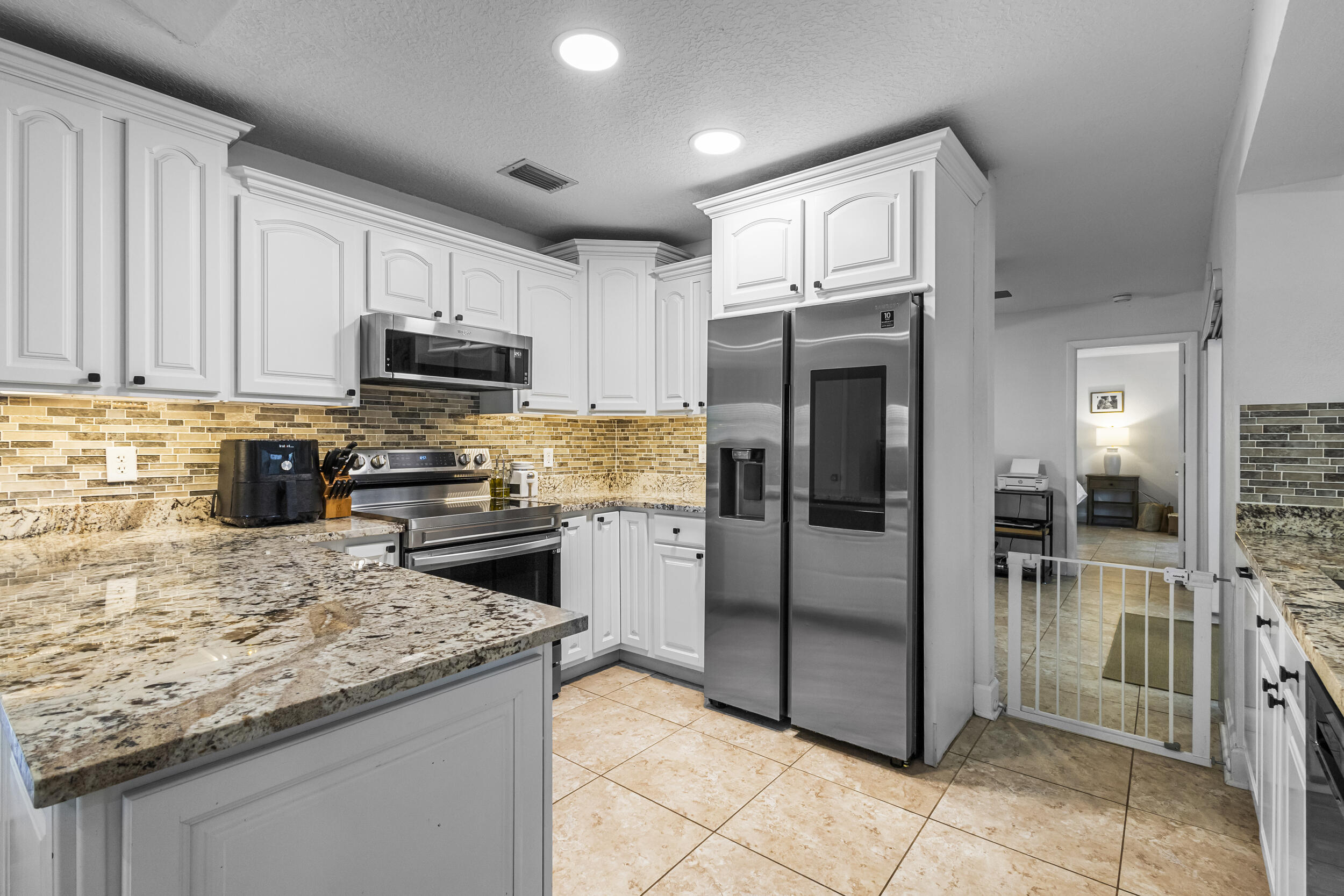 1948 Southwest 36th Avenue Delray Beach, FL 33445 - Photo 13 of 40 a kitchen with stainless steel appliances granite countertop a refrigerator sink and cabinets