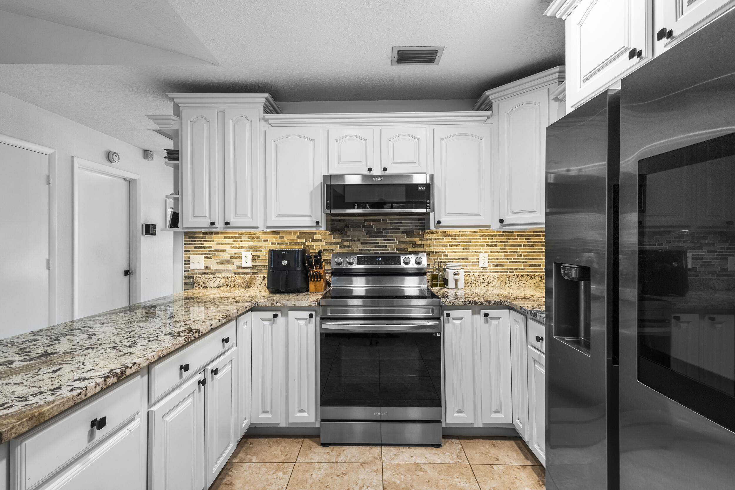 1948 Southwest 36th Avenue Delray Beach, FL 33445 - Photo 14 of 40 a kitchen with stainless steel appliances granite countertop a stove and a refrigerator